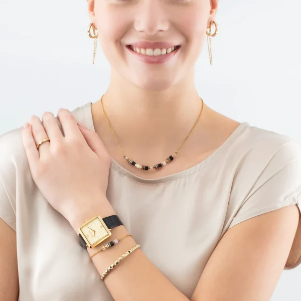 a woman wearing a gold watch and necklace